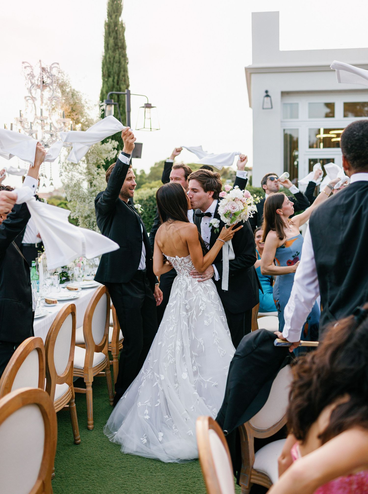Wedding guests enthusiastically wave napkins during a festive reception celebration on an outdoor terrace at Castel Bay, Hyères.