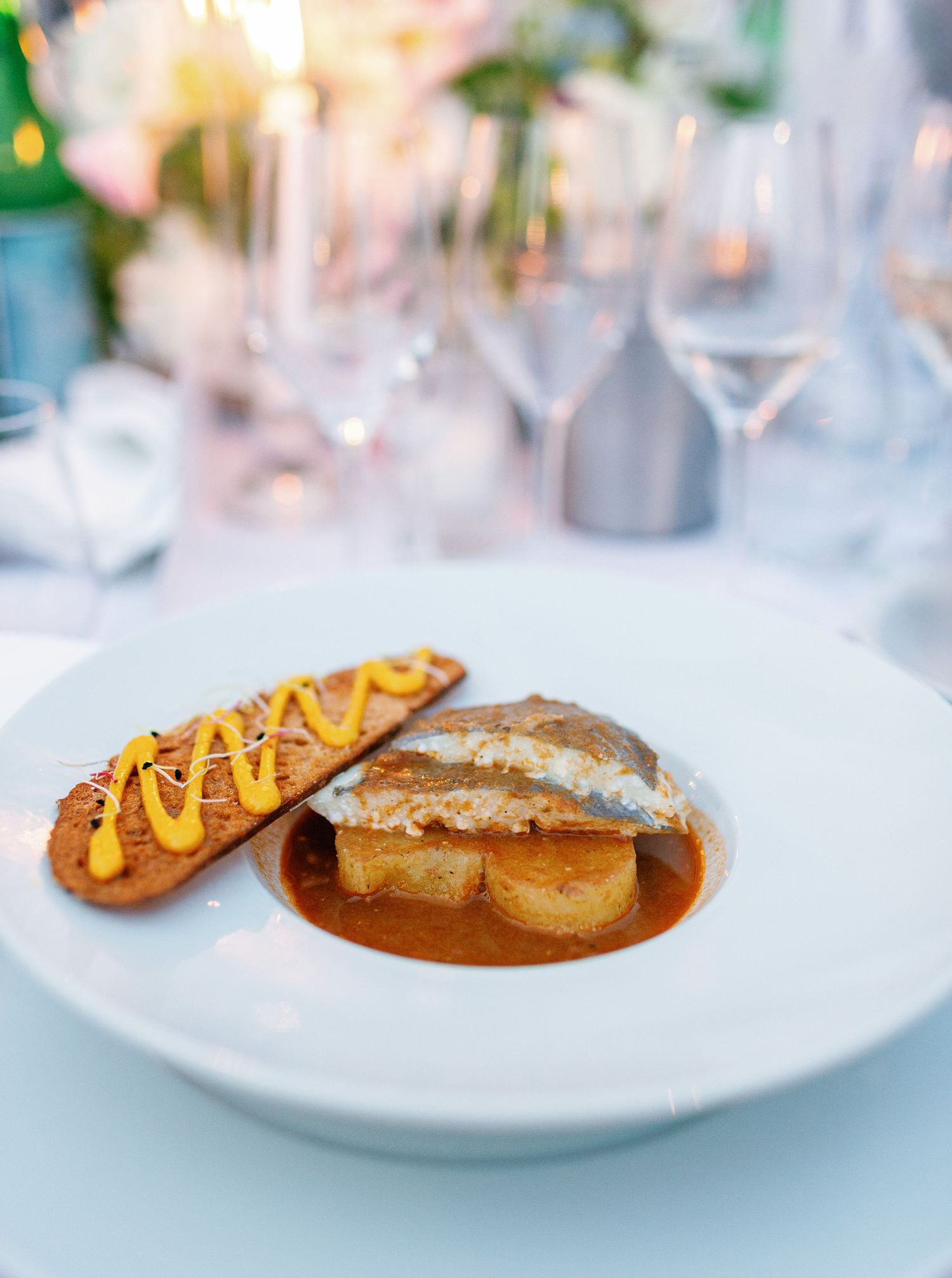 Elegant plated dish featuring a grilled meat in brown sauce with a side of golden yellow corn garnish.