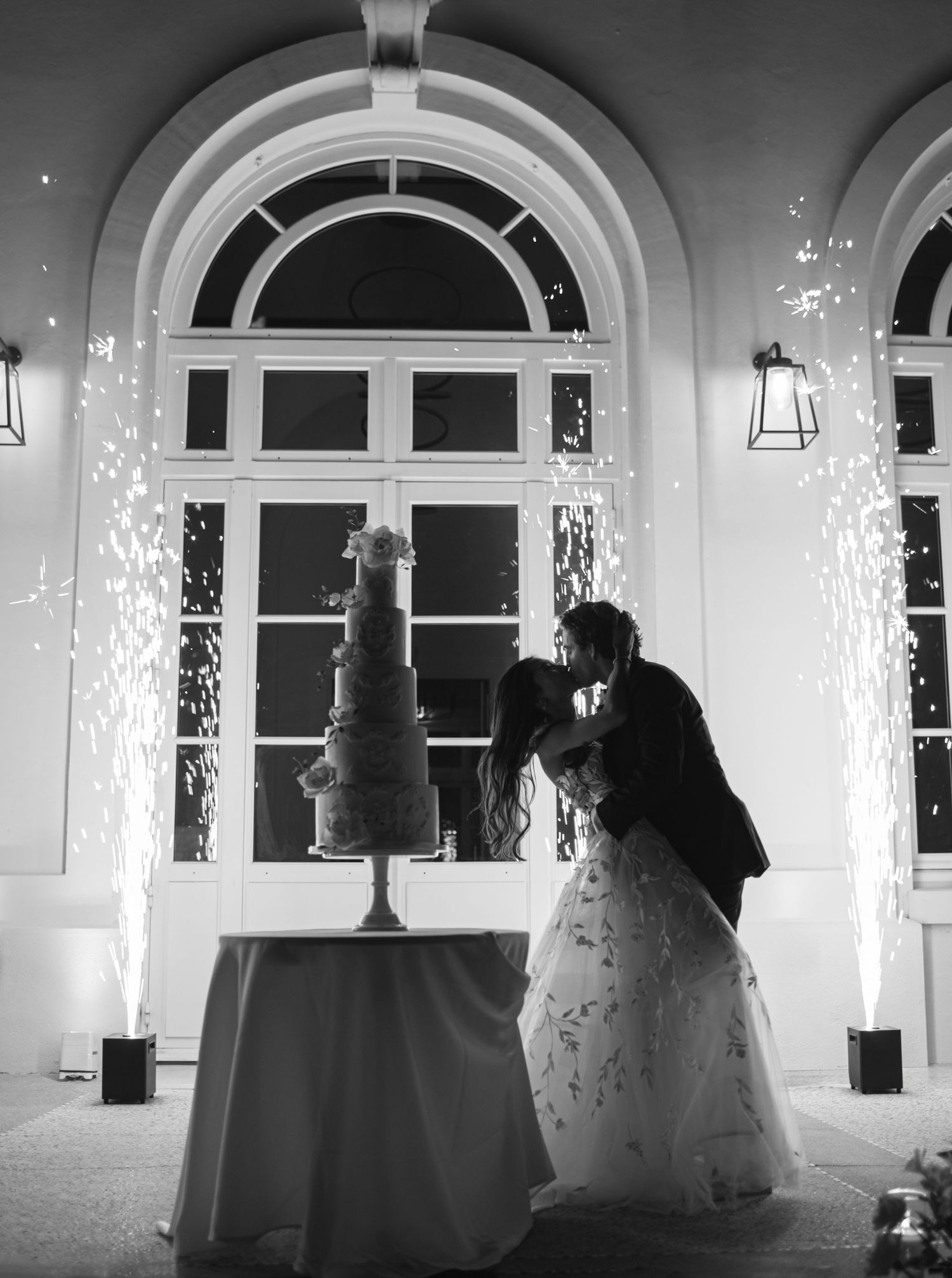 A panoramic series showing a romantic wedding cake scene and newlyweds kissing in black and white with elegant arched windows.
