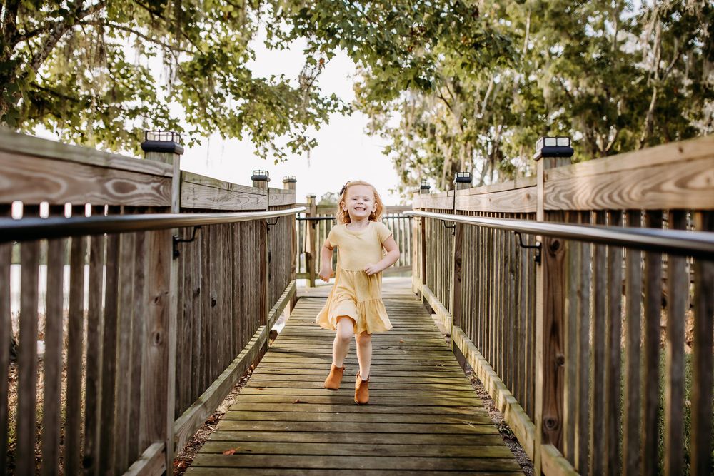A wooden boardwalk path with wooden railings leads through lush foliage in a natural setting.