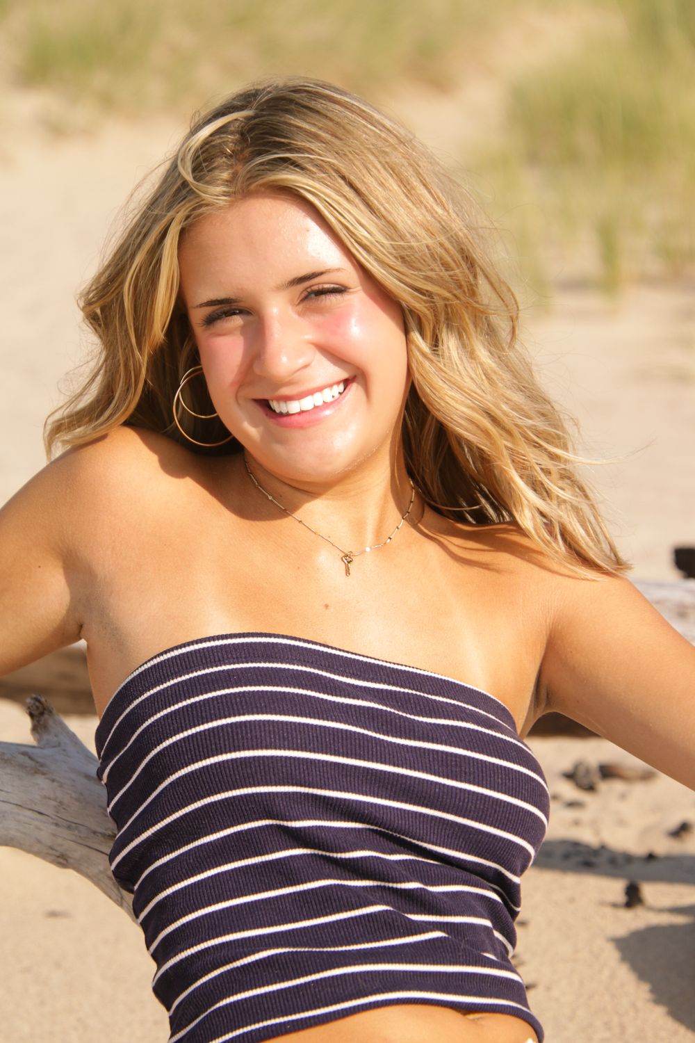 Casual beach portrait with striped top against natural dune background.
