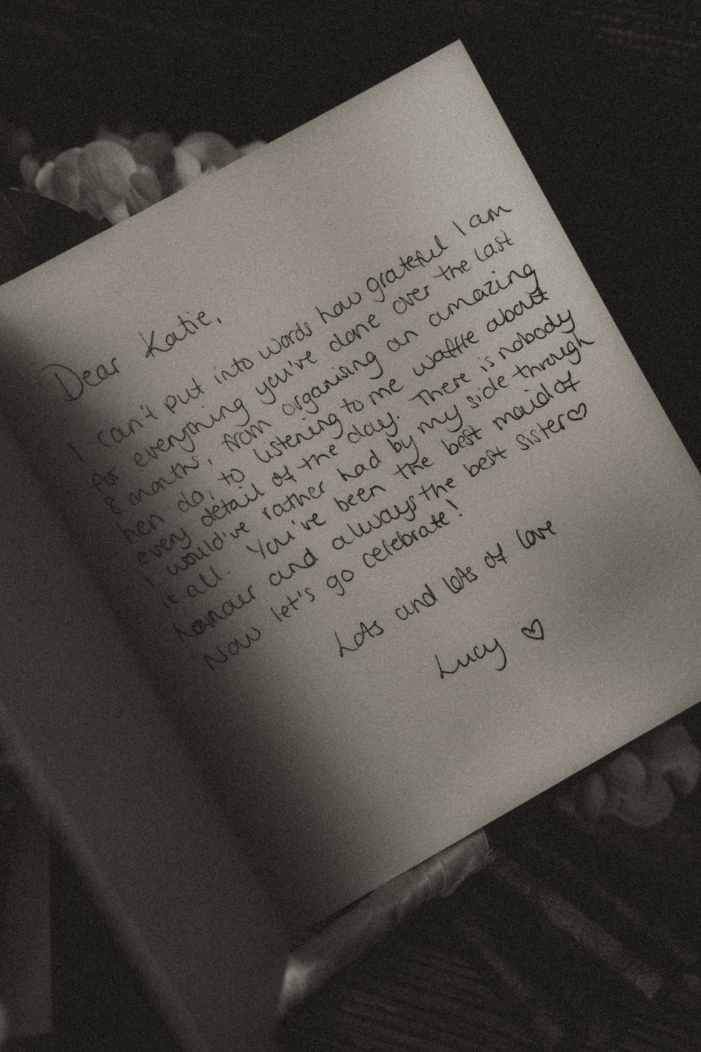 A handwritten love letter in black and white shows personal message with words of affection on white paper.