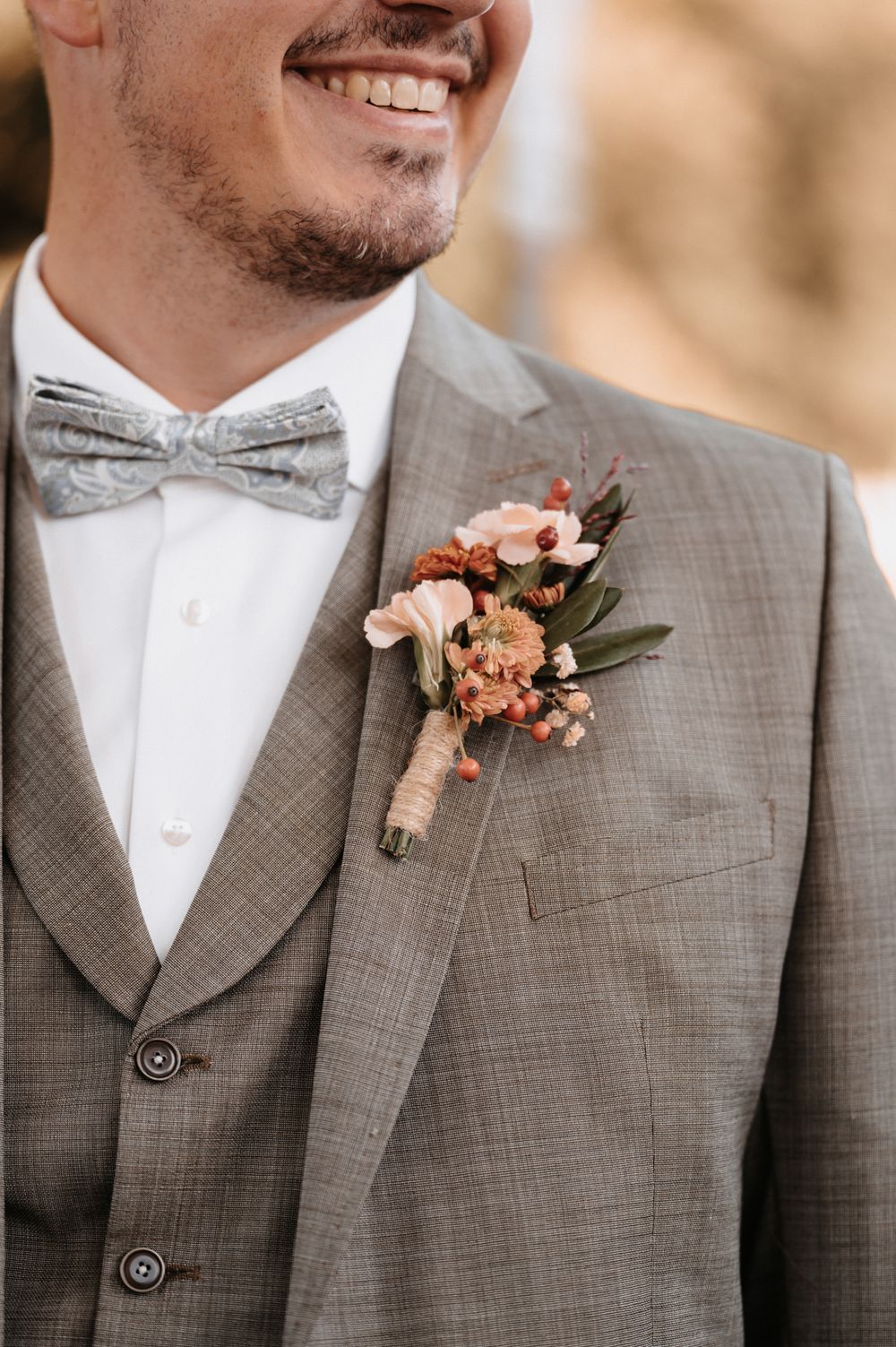 Detailaufnahme Bräutigam: Mund, Jacket, Fliege und Blumenbouquet