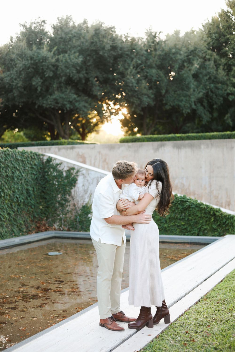 Sweet family portrait series on concrete steps with sunset lighting and trees in background.