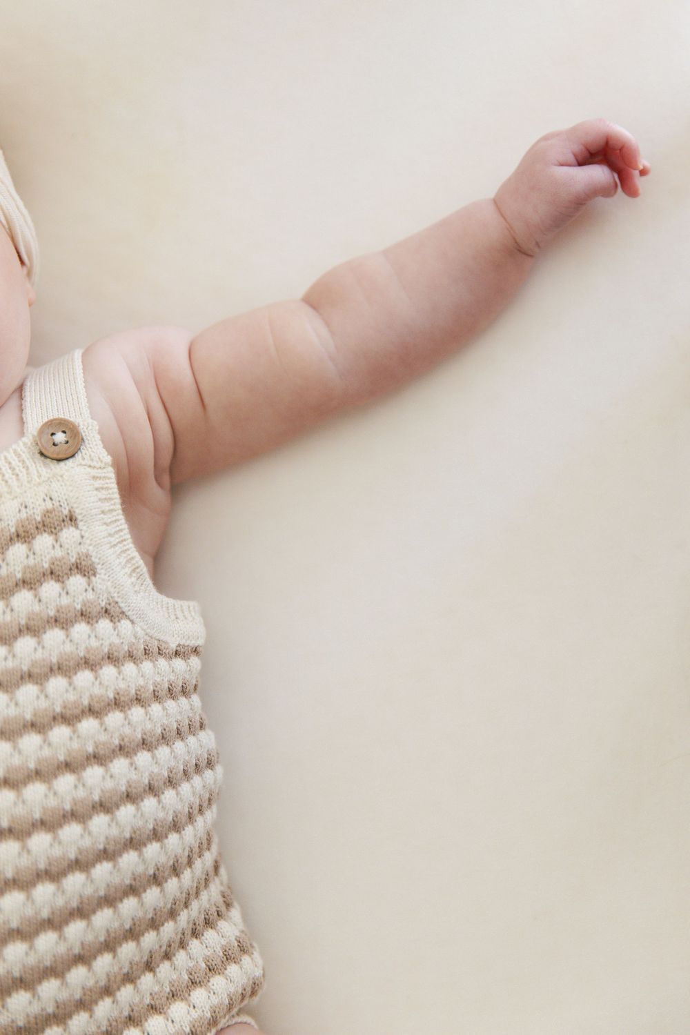 Close-up details of knitted baby clothing pattern in neutral tones.