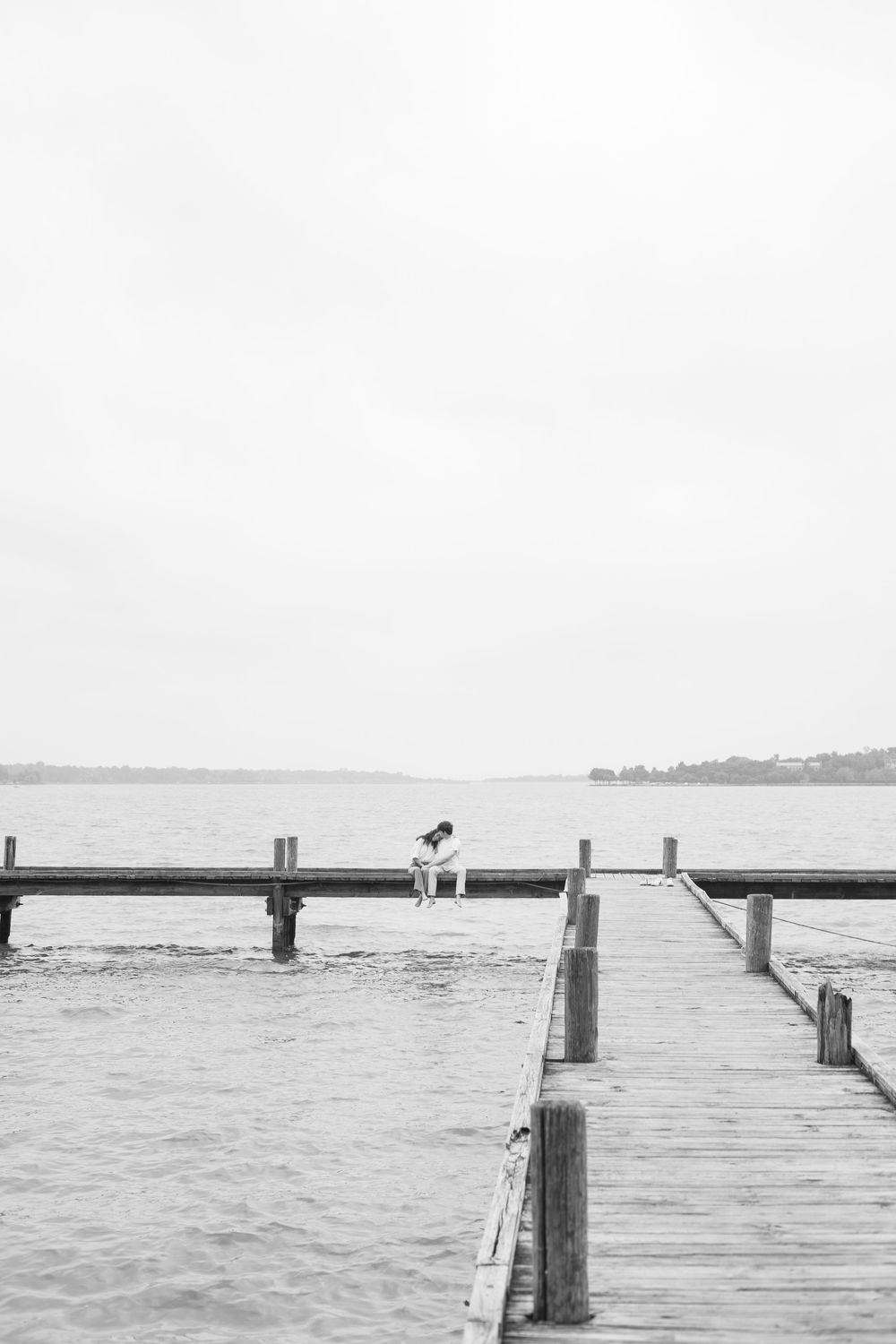 Minimalist black and white photos of wooden pier extending into calm waters.