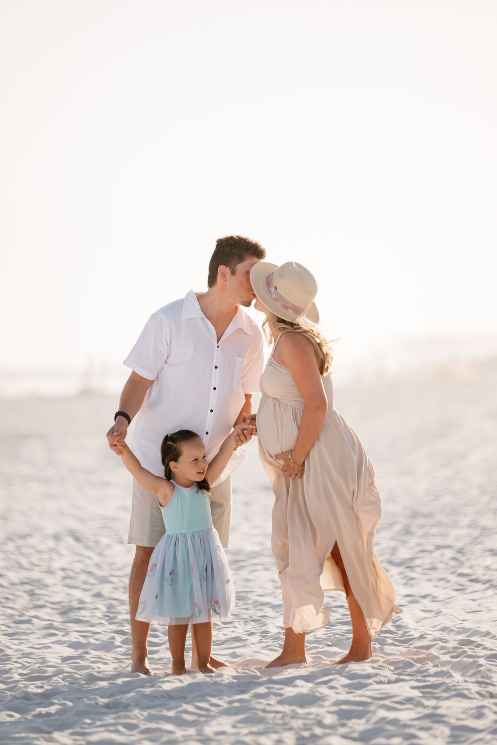 A sweet family moment captured in sequence at sunset on a white sandy beach.