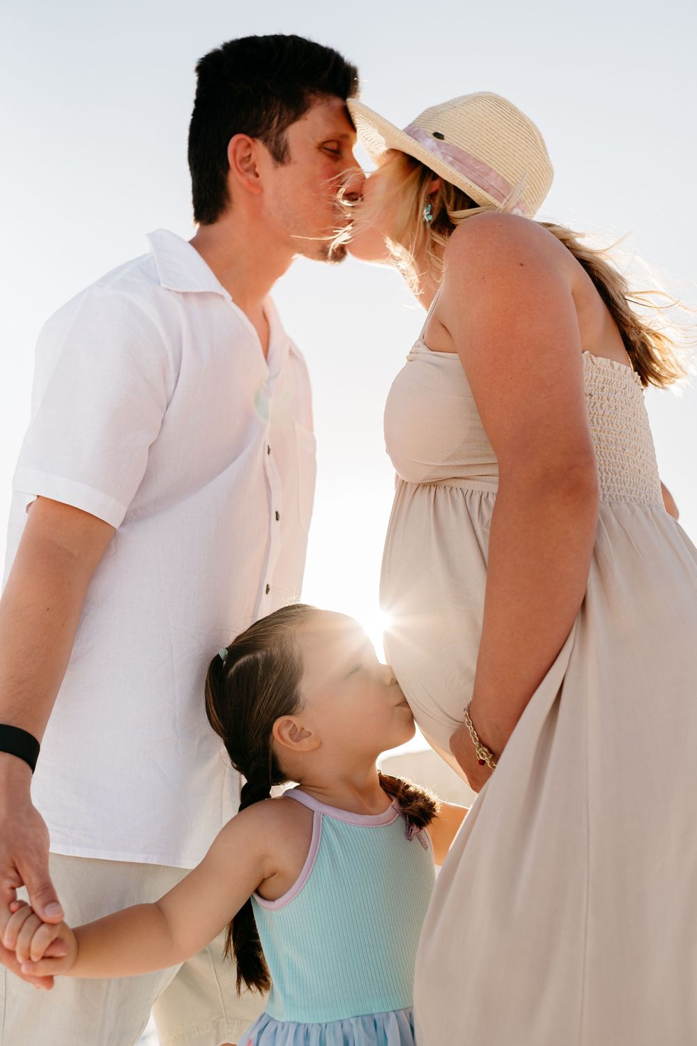 Romantic couple photos in white outfits against sunset with backlit silhouettes showing movement and intimacy.
