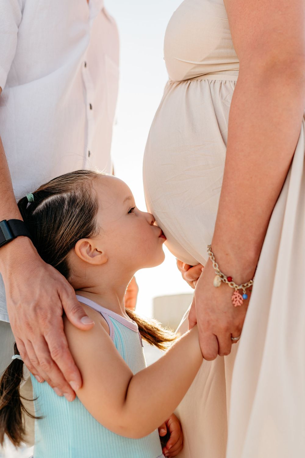 A series of intimate side-view portraits showing a parent and child embracing on the beach.