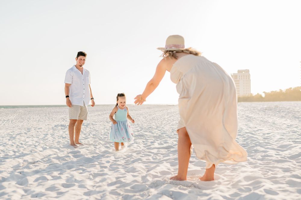 Family walking together and playing on a white sandy beach at sunset creating joyful moments together.