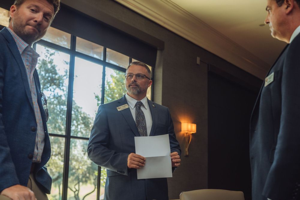 Three business professionals having a discussion while reviewing documents in an office setting.