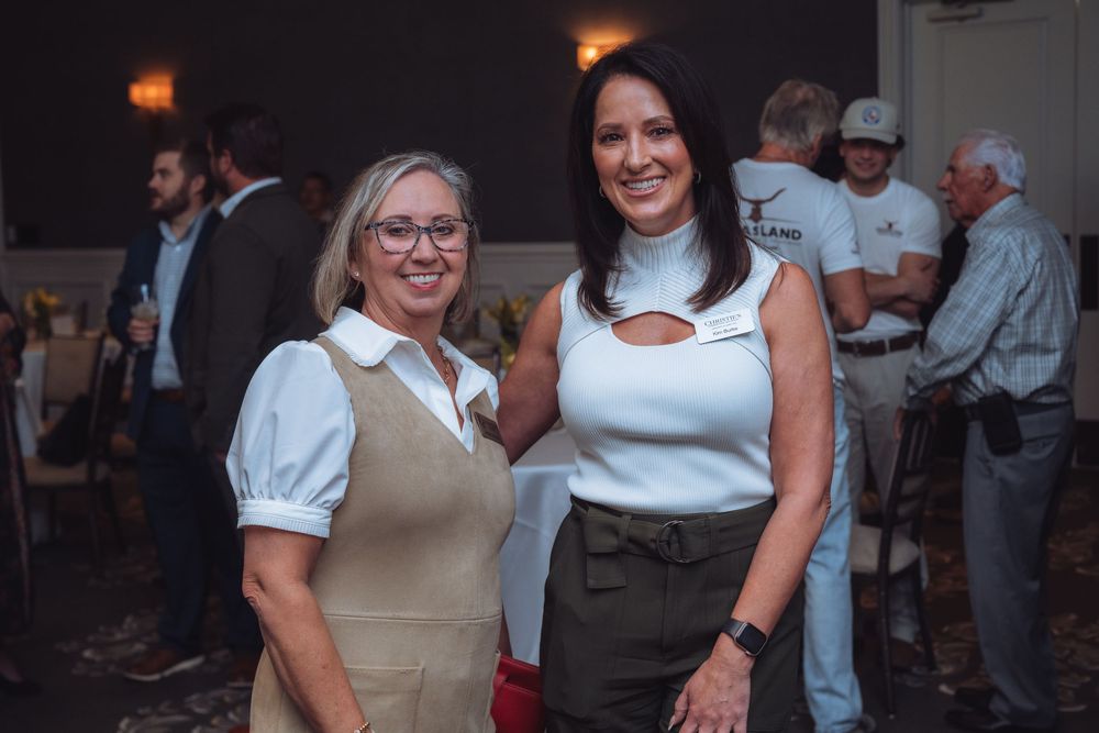 Two professionals posing together at a business networking event.