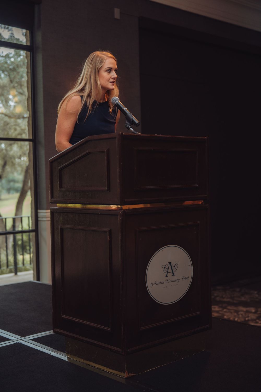 Professional speaker delivering presentation at wooden podium during business event.