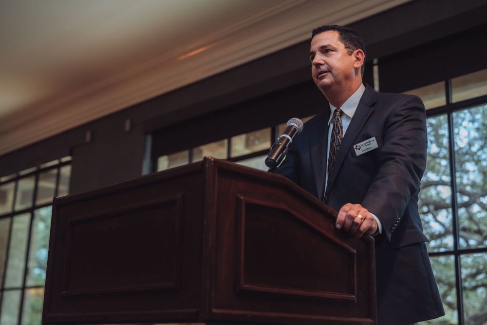 Speaker presenting from a wooden podium at formal business event.