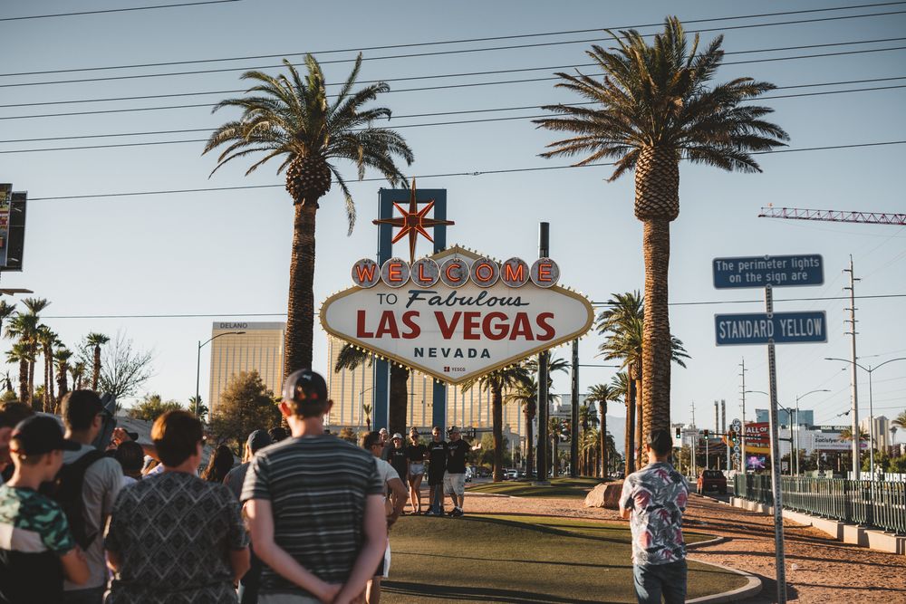 Palm tree-lined street with iconic Welcome to Las Vegas sign visible in panoramic view.