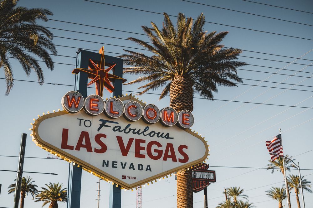 Famous Welcome to Fabulous Las Vegas sign with palm trees and blue sky during daytime.
