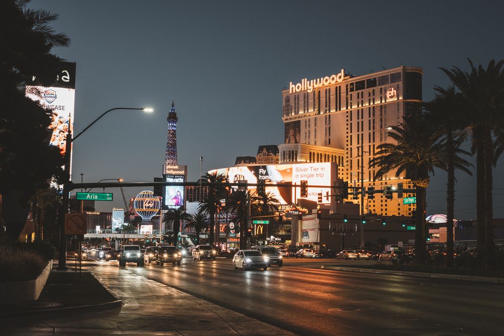Nighttime view of Las Vegas Boulevard with lit buildings and street lights creating an urban glow.