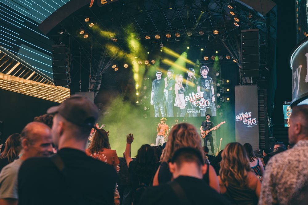 Music festival crowd watching performance with dramatic yellow lighting and stage effects.