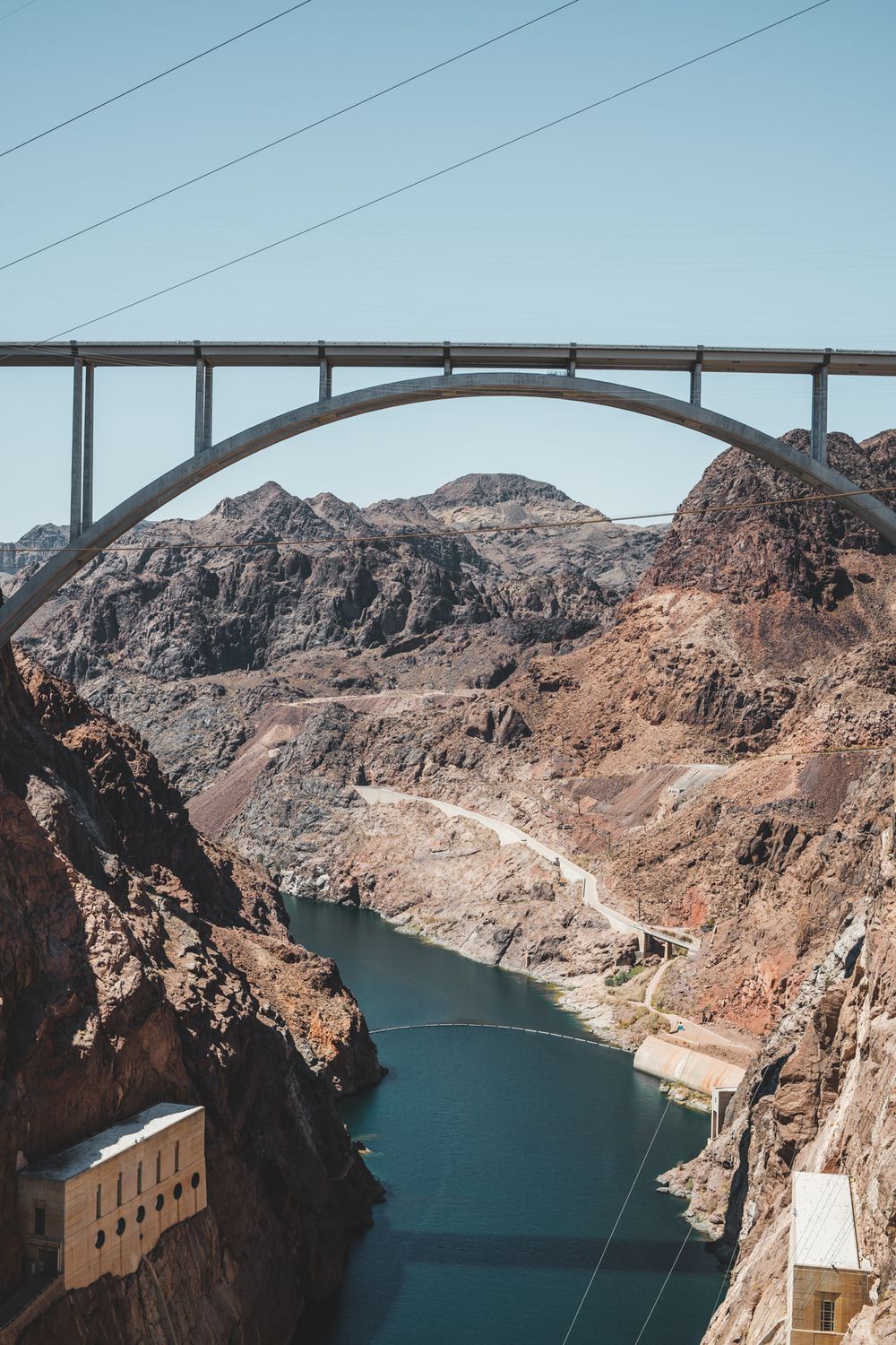 Arch bridge spanning deep canyon with turquoise reservoir waters below.