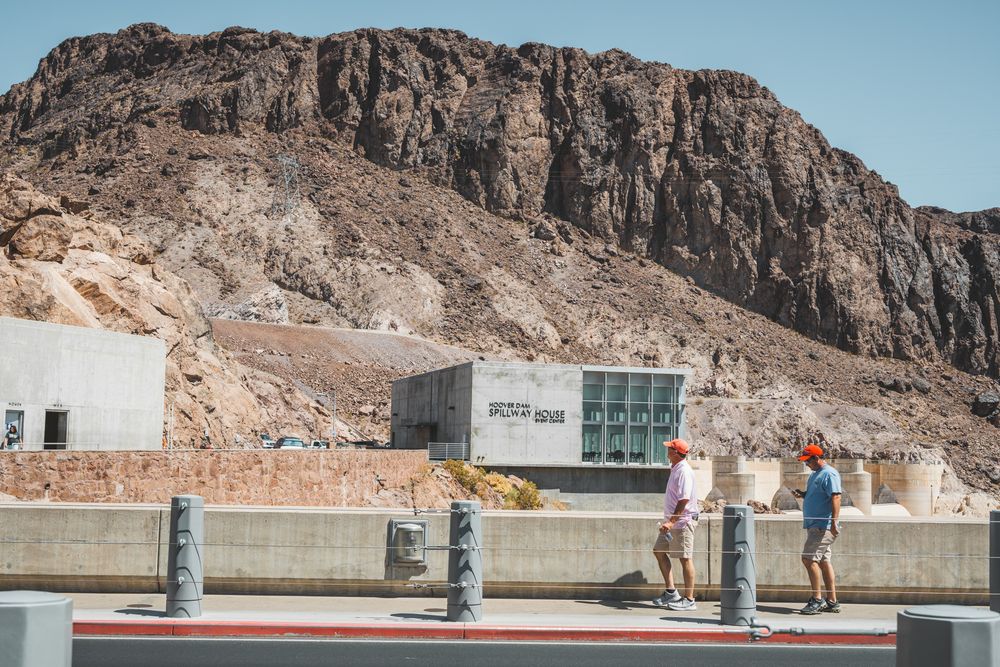 Visitors at Hoover Dam viewing area with rocky cliff backdrop.