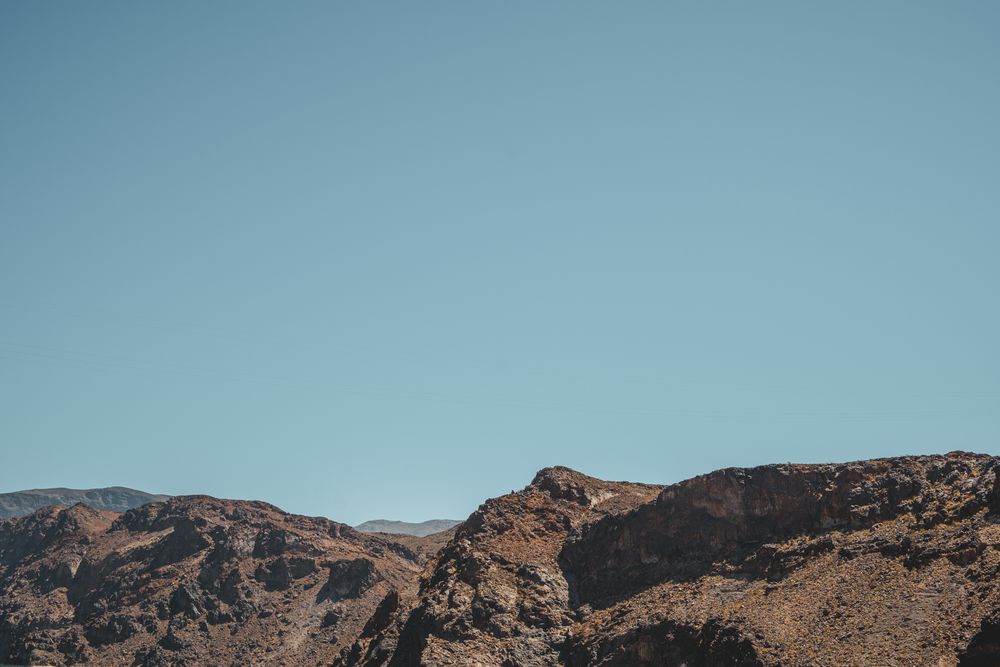 Rugged desert mountain peaks against clear blue sky.