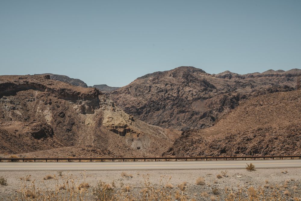 Barren desert mountain landscape with rocky outcrops and clear blue sky.