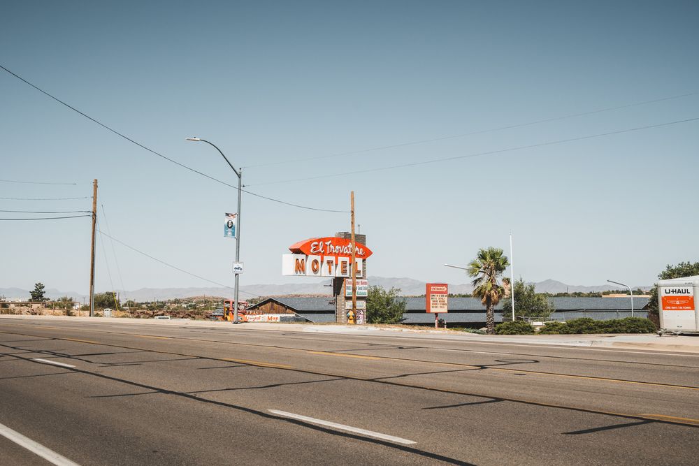 Vintage roadside motel sign along desert highway with utility poles.