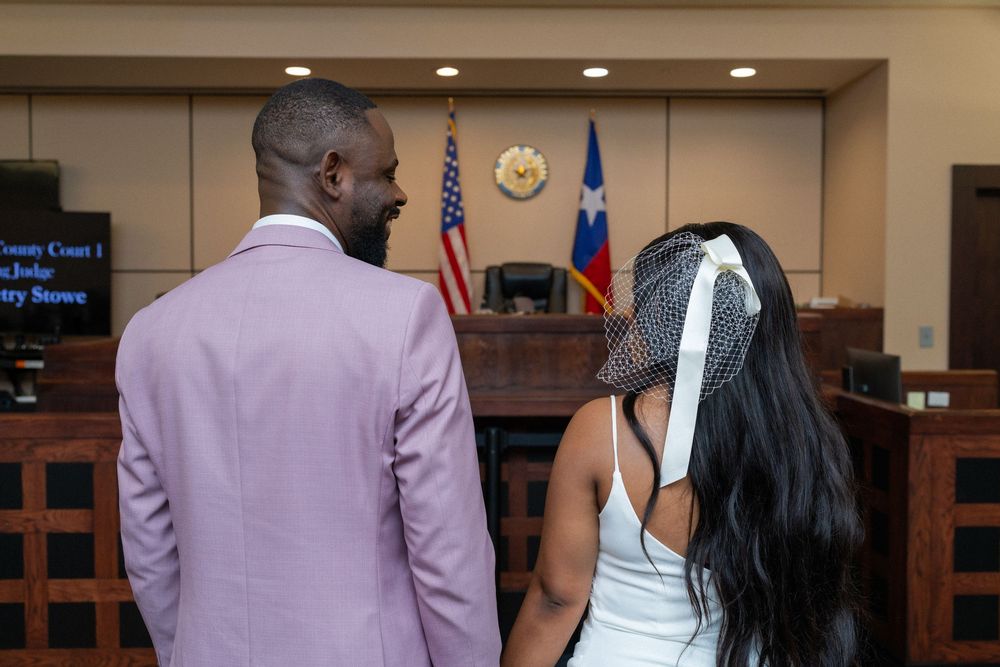 Couple stands before judge's bench during intimate courthouse wedding ceremony.