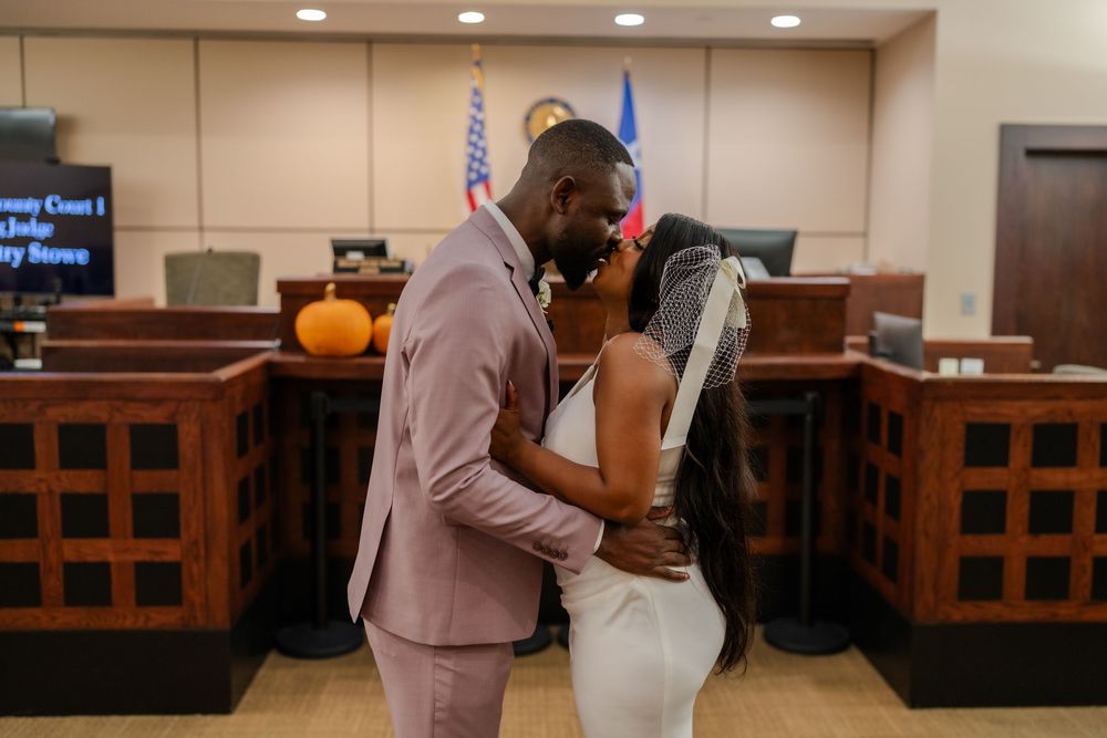 A couple celebrates their union in a courthouse with wooden paneling and overhead lighting.
