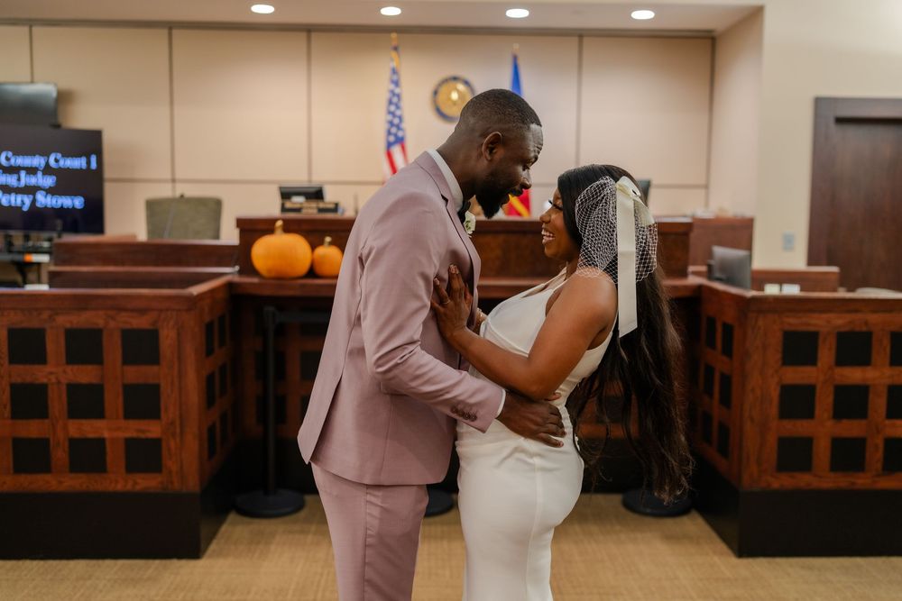 A romantic moment captured between newlyweds in a government building hallway.