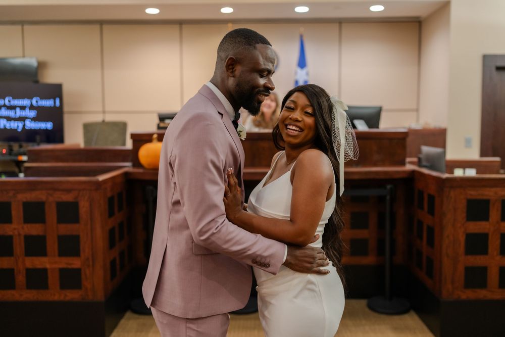 A joyful embrace between newlyweds in a courthouse setting with autumn decorations.