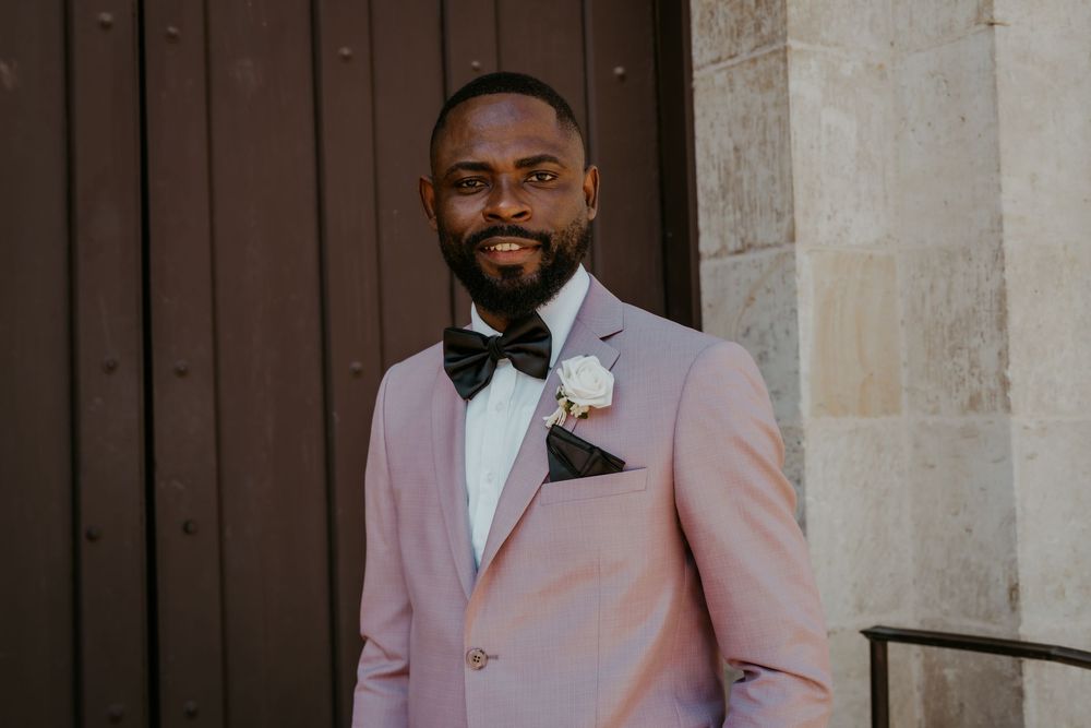 A wedding portrait against a stone wall backdrop with elegant formal attire.