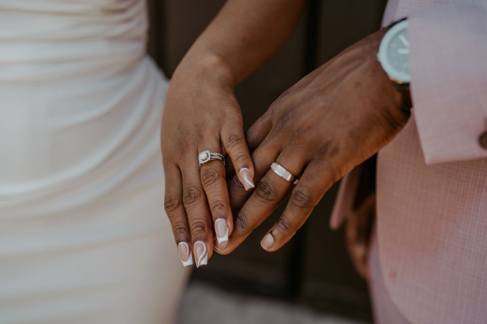 Intimate close-up of hands showing wedding rings and formal attire.