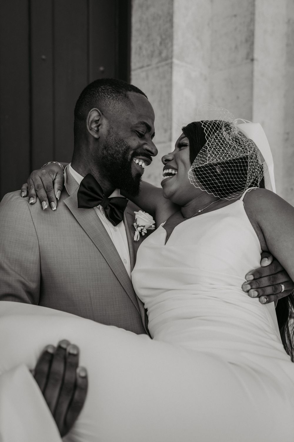 Black and white close-up of newlyweds sharing a joyful laugh together.