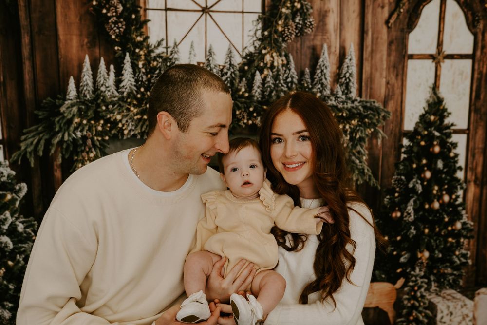 Family portrait with warm lighting and Christmas decorations in the background.