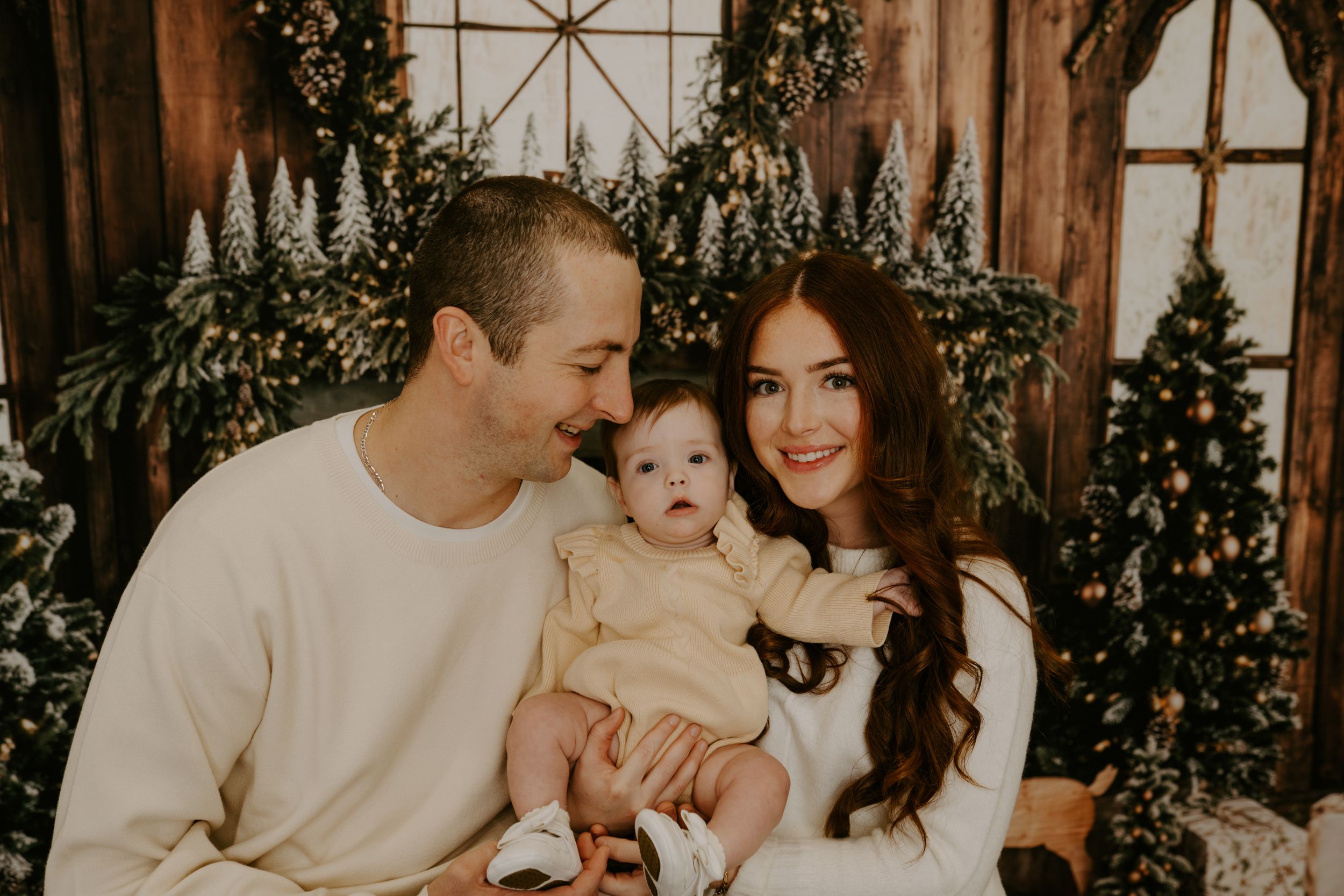 Family portrait with warm lighting and Christmas decorations in the background.