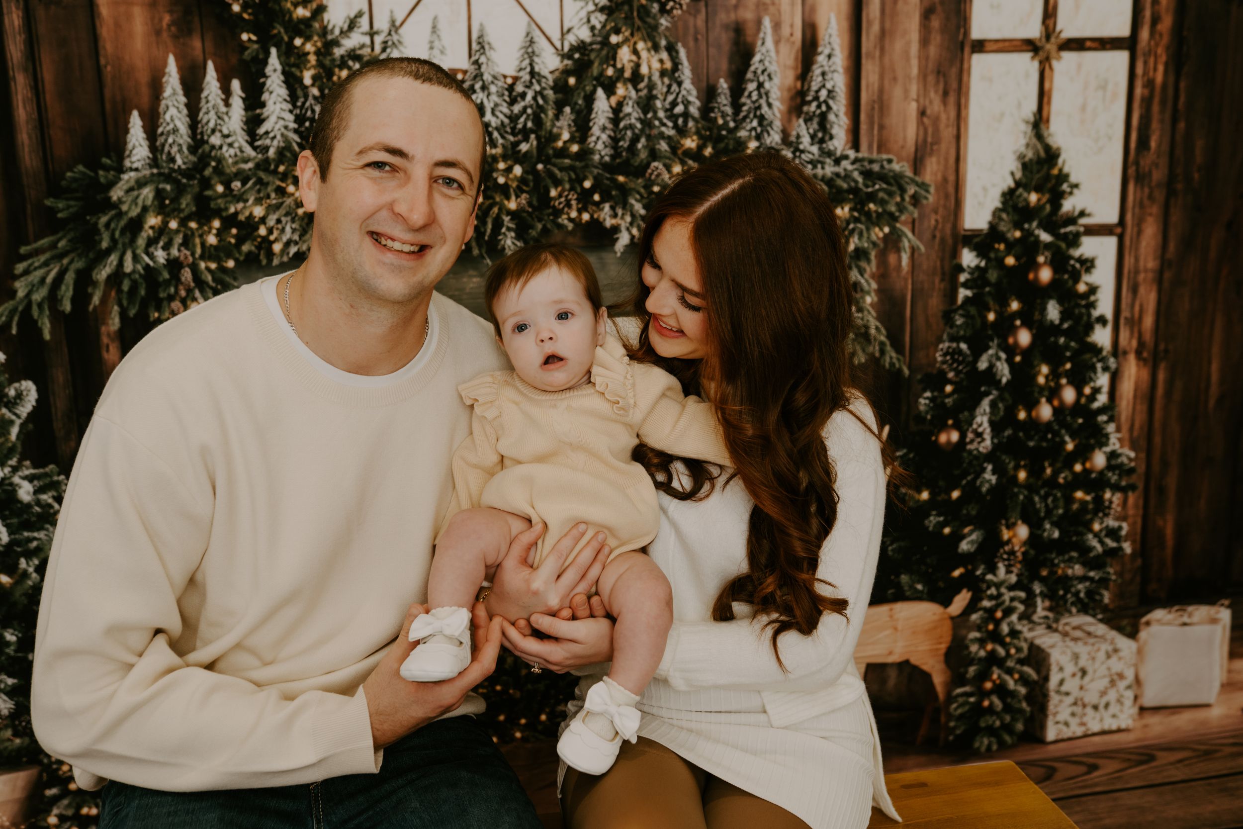 Holiday family portrait with festive greenery and string lights in background.