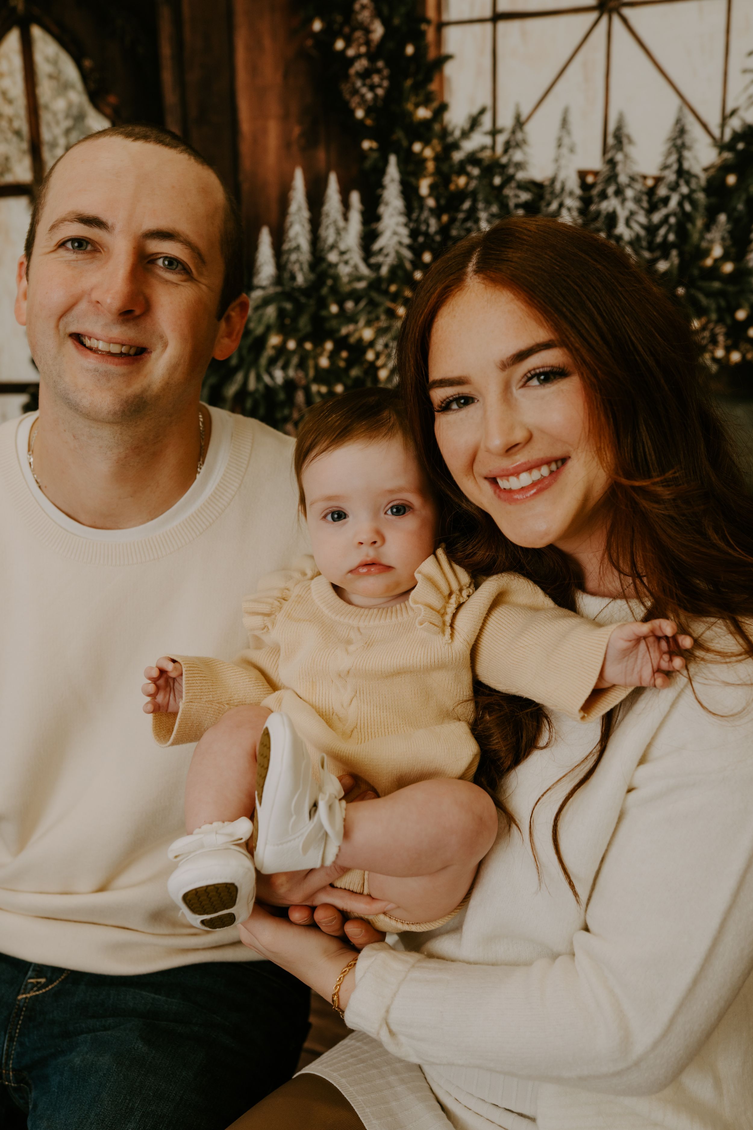 Warm family portrait with Christmas decorations and rustic wooden backdrop.