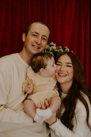 Joyful family photo session with everyone laughing against a red curtain background.