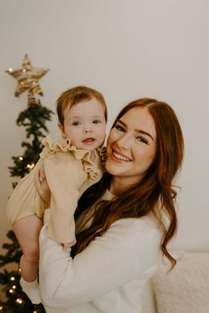 A heartwarming holiday portrait in front of a Christmas tree with soft lighting and warm tones.