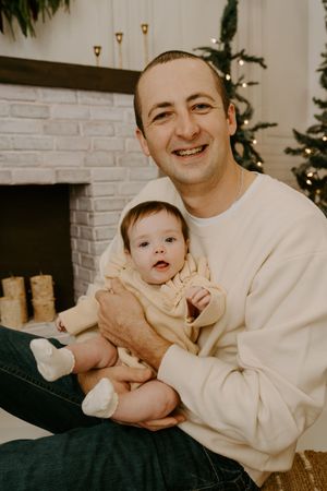 A tender moment between parent and child during a Christmas photoshoot by the fireplace.