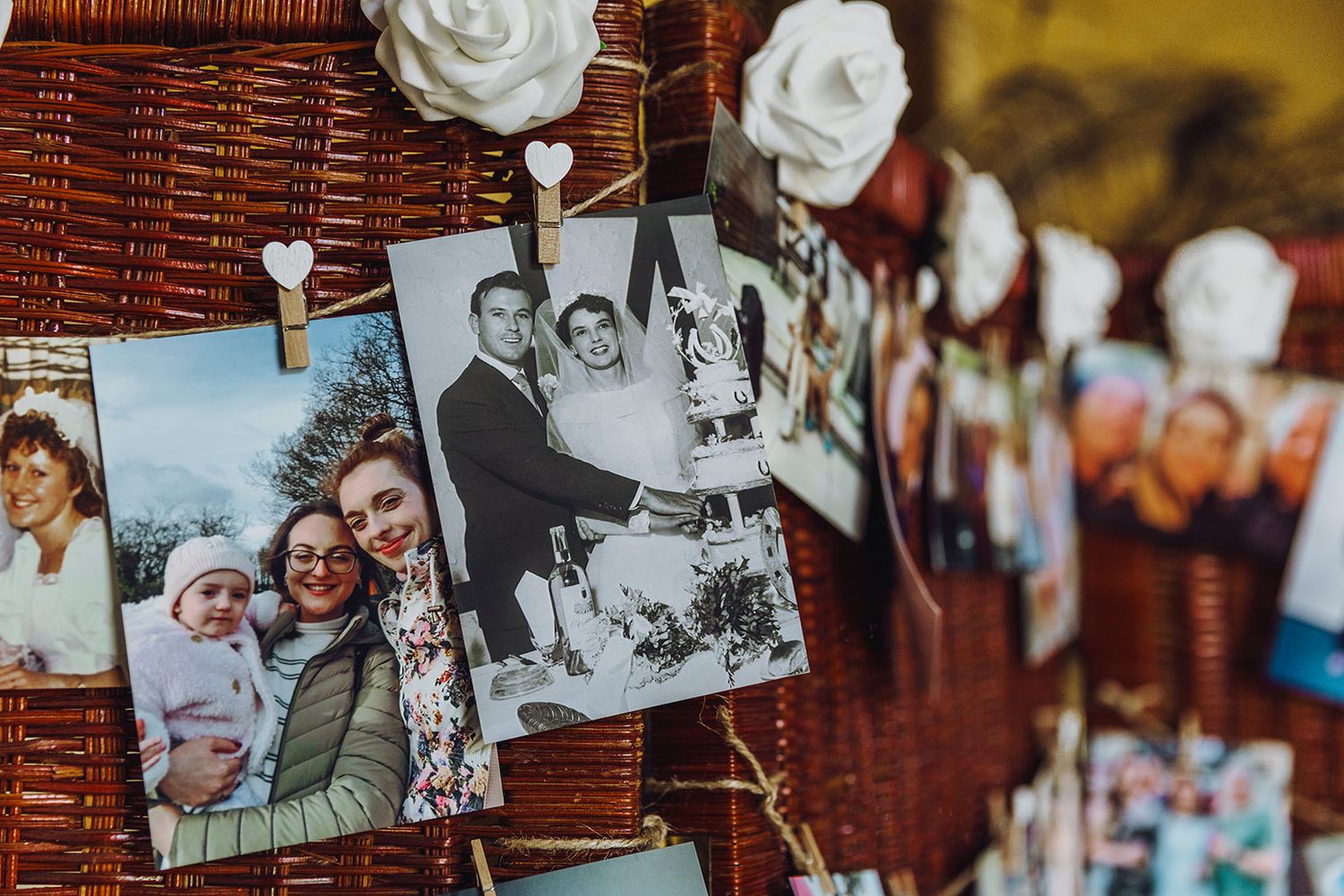 Collection of vintage black and white photographs displayed on a rustic brown woven wall.