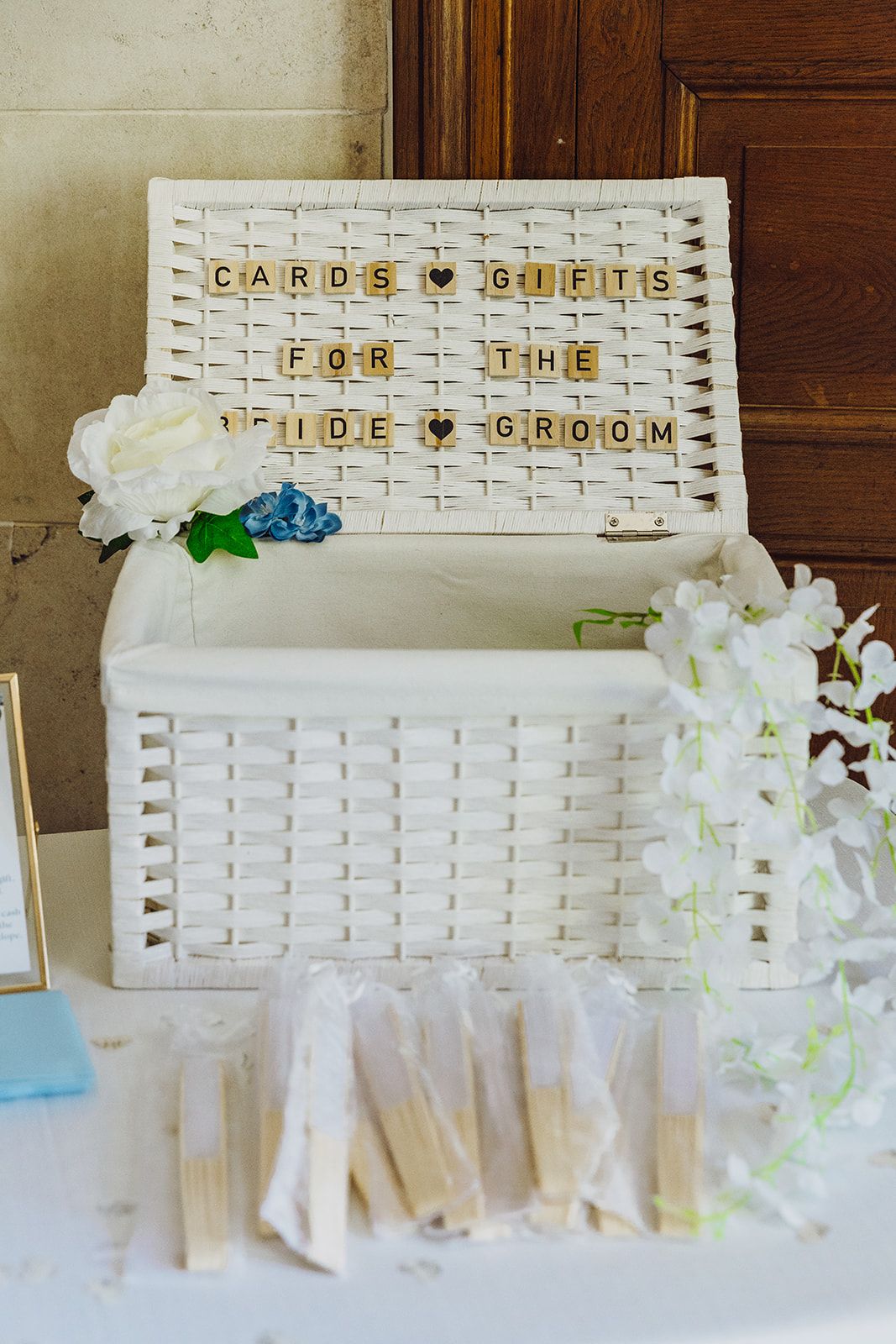 White woven baskets with letter tiles spelling out 'Cards & Gifts' and 'For The' arranged at a wedding gift table.