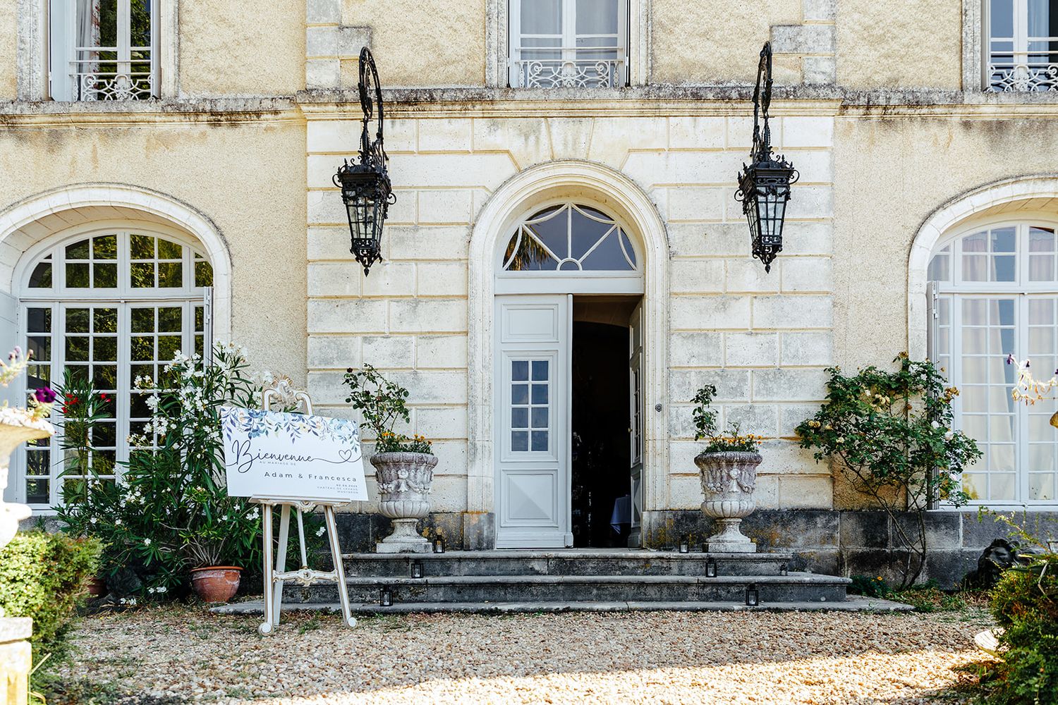 Elegant French chateau with classic stone architecture, arched windows, and hanging lanterns along its facade.
