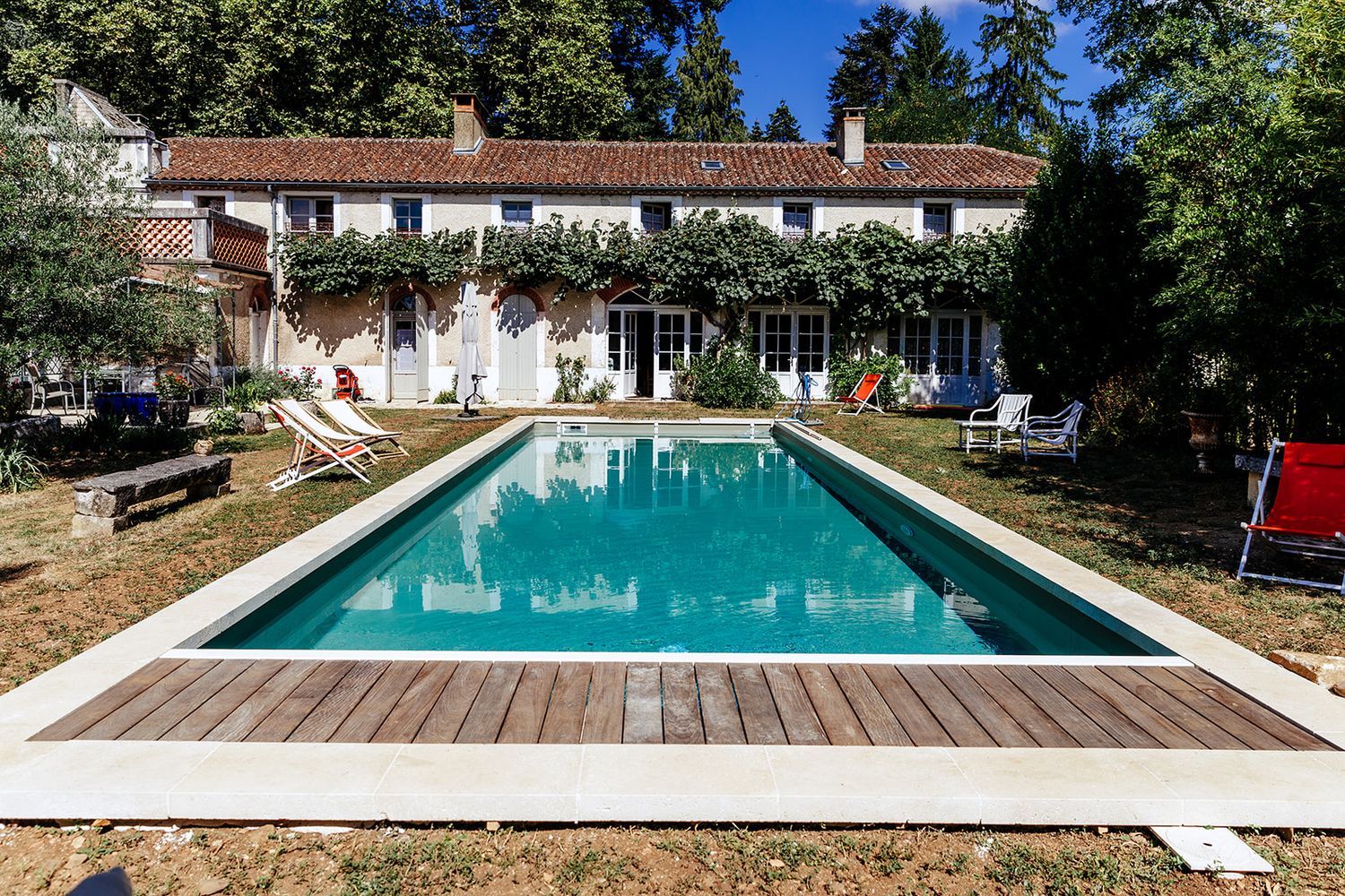 Large rectangular swimming pool surrounded by manicured lawn and trees at an elegant countryside estate.