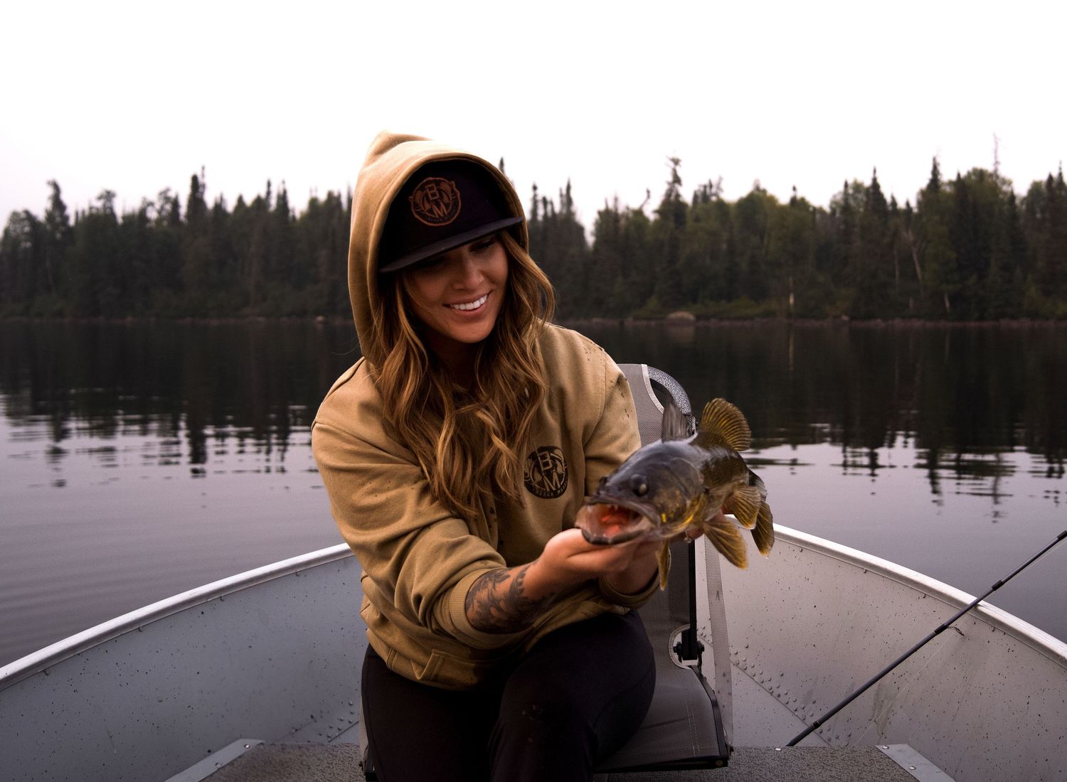 Fishing on a calm lake during sunset with fishing rod in hand.