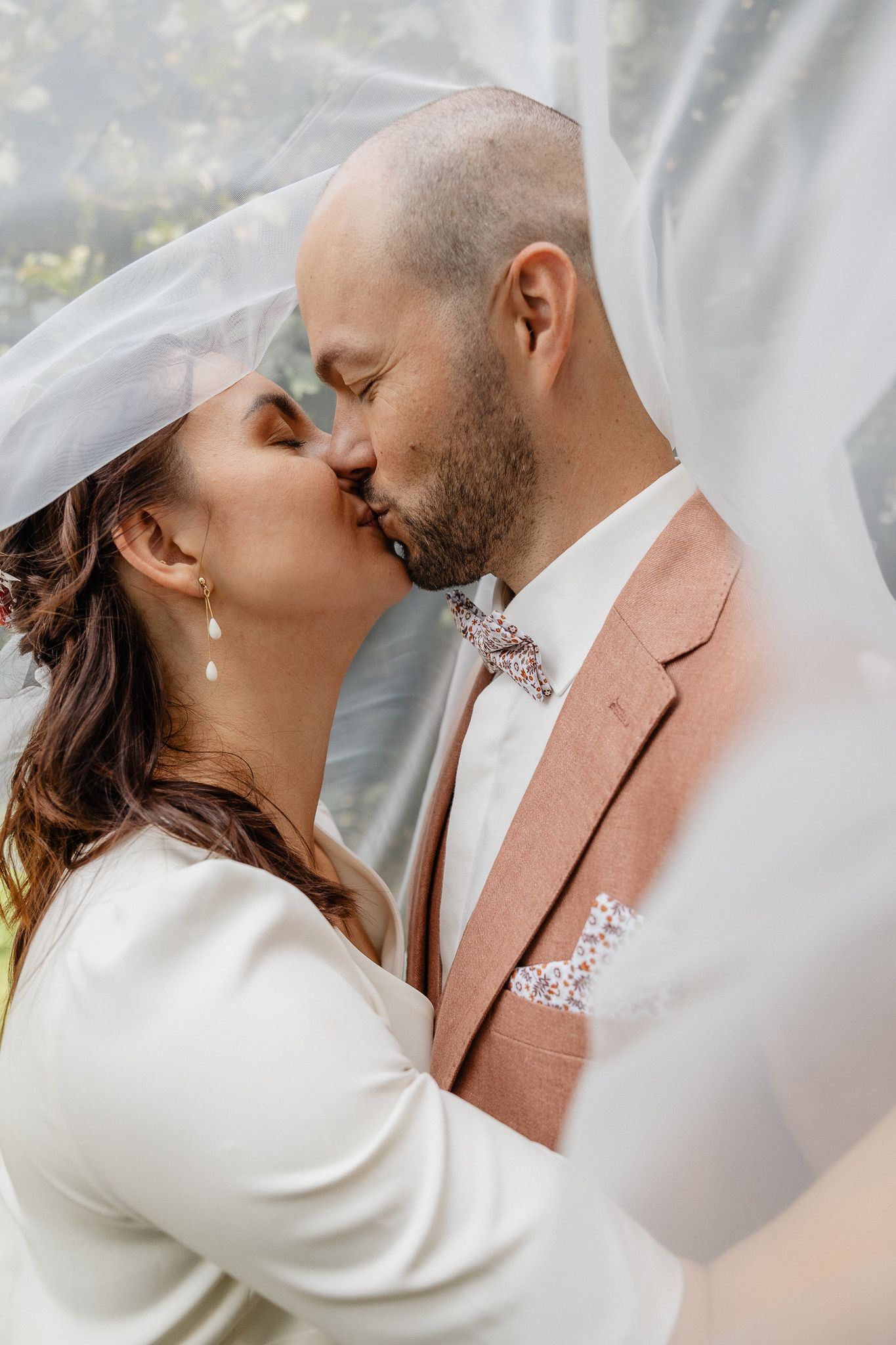 Photo d'un couple de maries s'embrassant sous le voile pendant un reportage photo de mariage civil a Lille