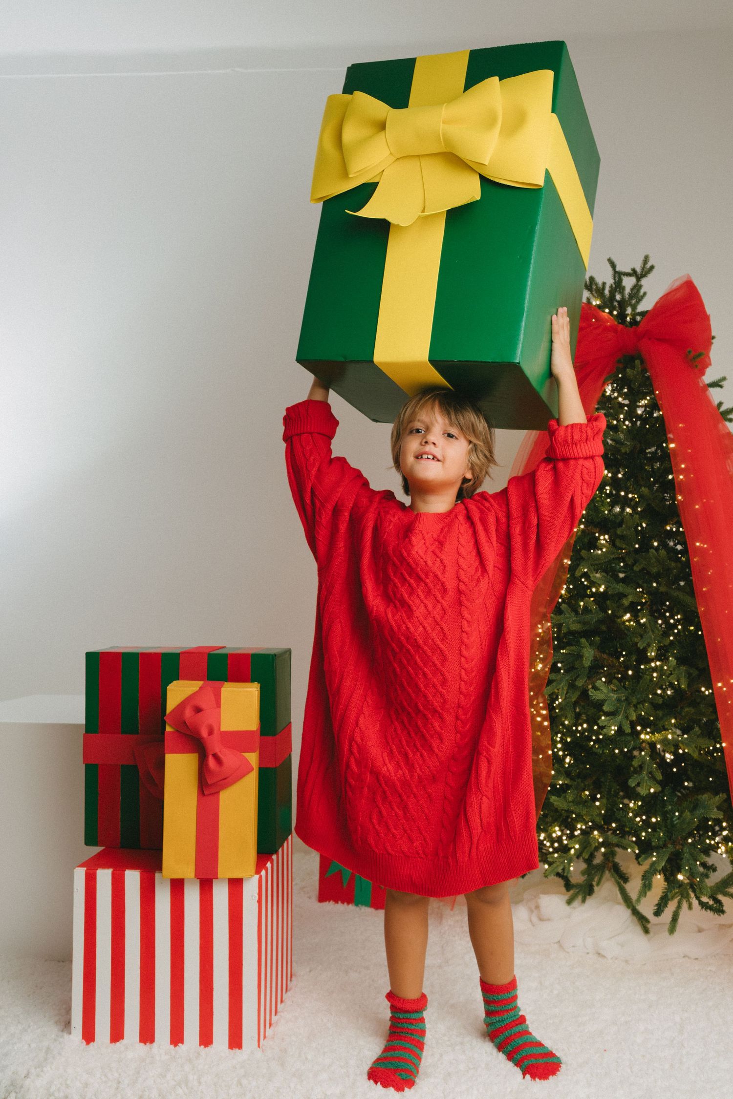 A series of festive Christmas photos showing a red sweater and large green gift boxes with yellow bows against a decorated tree.