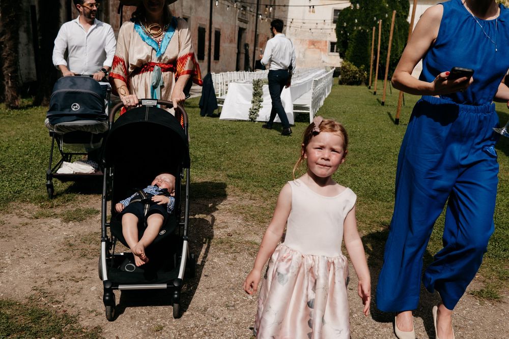 Children in formal attire walking down a grassy aisle at an outdoor wedding ceremony.