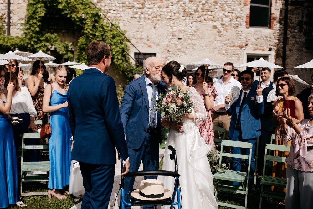 Wedding guests gather outdoors at a rustic venue with exposed brick walls and blue bridesmaid dresses.